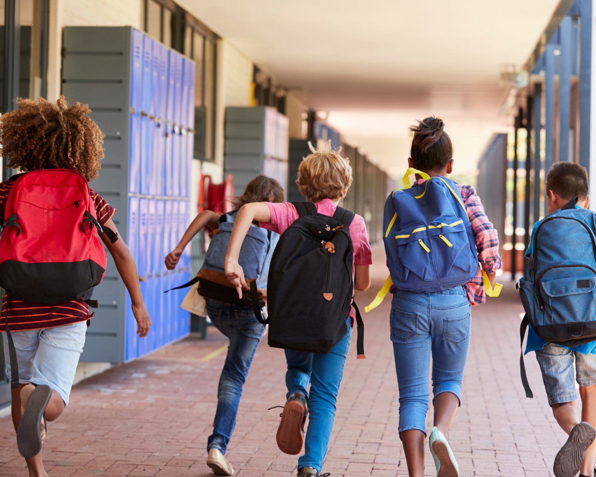 Enfants heureux courant vers l'école avec leurs cartables le jour de la rentrée des classes.